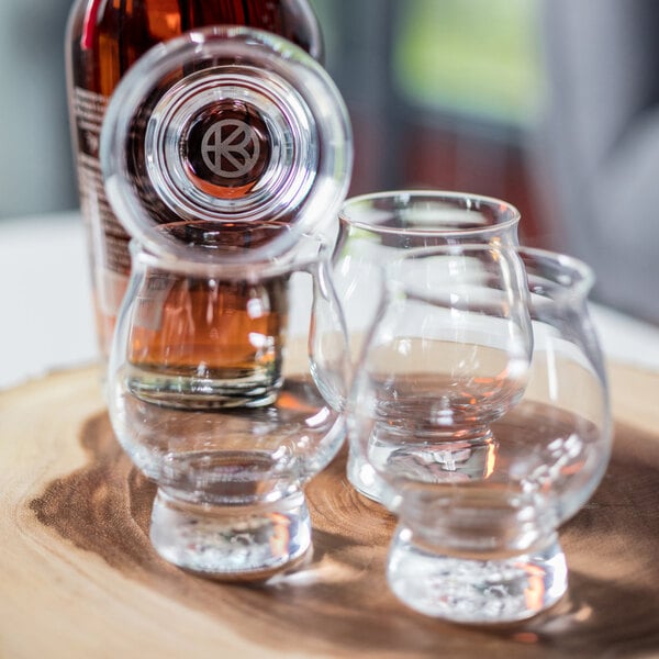 A set of clear, customizable Kentucky Bourbon Trail tasting glasses displayed on a wooden surface.