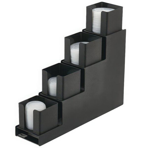 A black plastic Vollrath countertop lid holder with four steps holding white plastic lids.