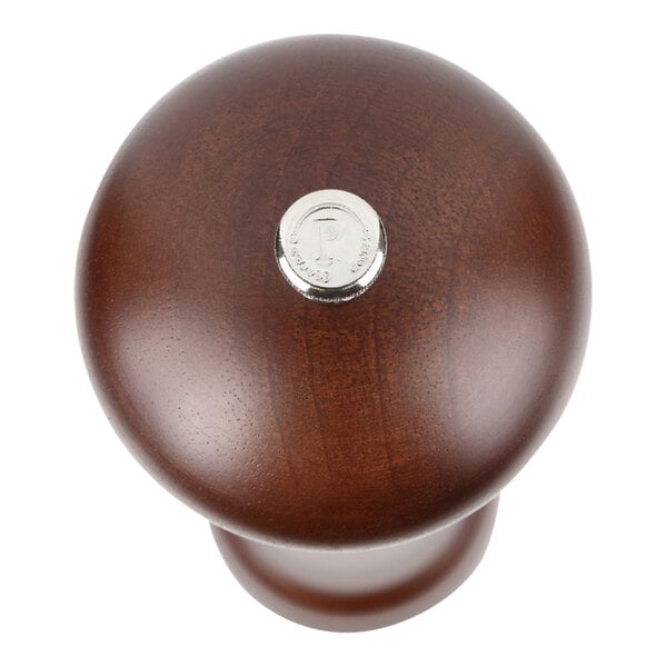 A close up of the top of a Chef Specialties walnut pepper mill with a silver metal button and wooden knob.