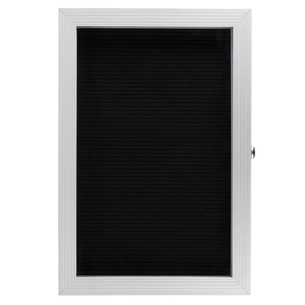 An Aarco black message board with a white frame and hinged door.