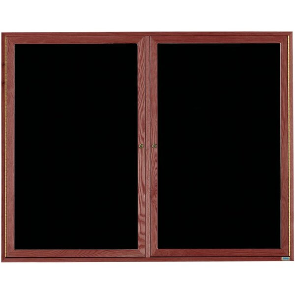 An Aarco black felt message board with a cherry frame and two black glass doors.