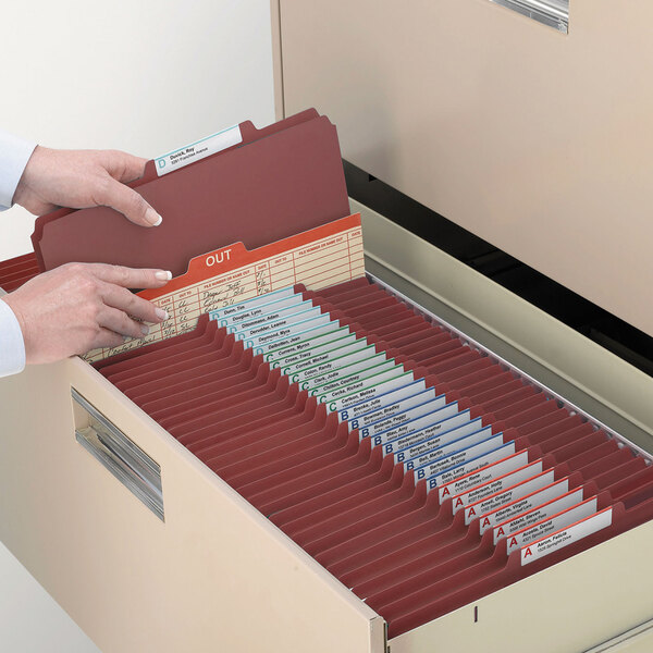 A hand opening a file drawer filled with Smead SafeSHIELD legal size classification folders.