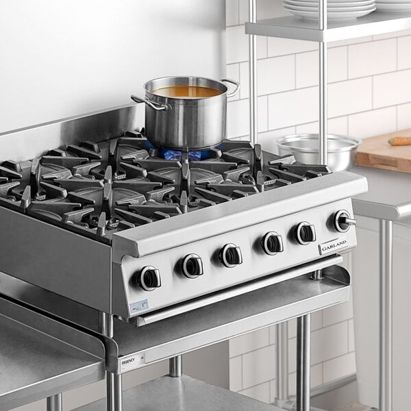 A stainless steel Garland GTOG36-6 liquid propane 6-burner countertop range with control knobs and a pot on one burner.