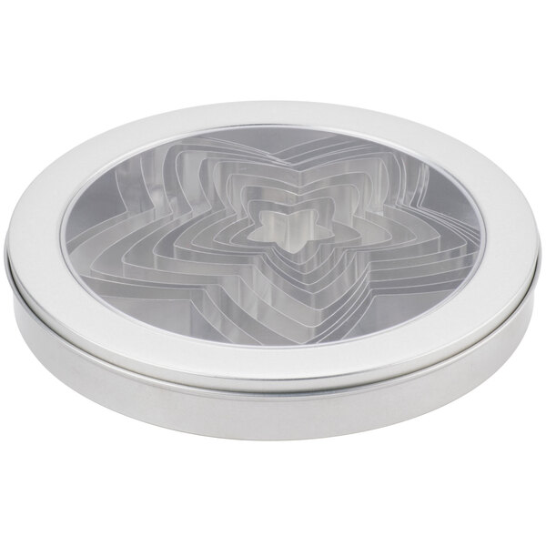 A circular silver metal tin with a circular design and Ateco 7808 stainless steel star cutters inside.