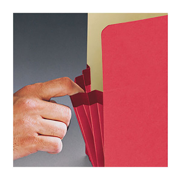 A hand opening a red Smead file pocket.