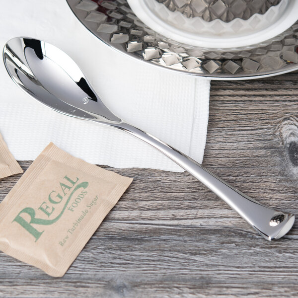 A Chef & Sommelier stainless steel teaspoon and a tea bag on a table.