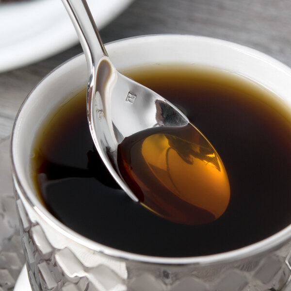 A Chef & Sommelier stainless steel teaspoon with liquid in a cup.