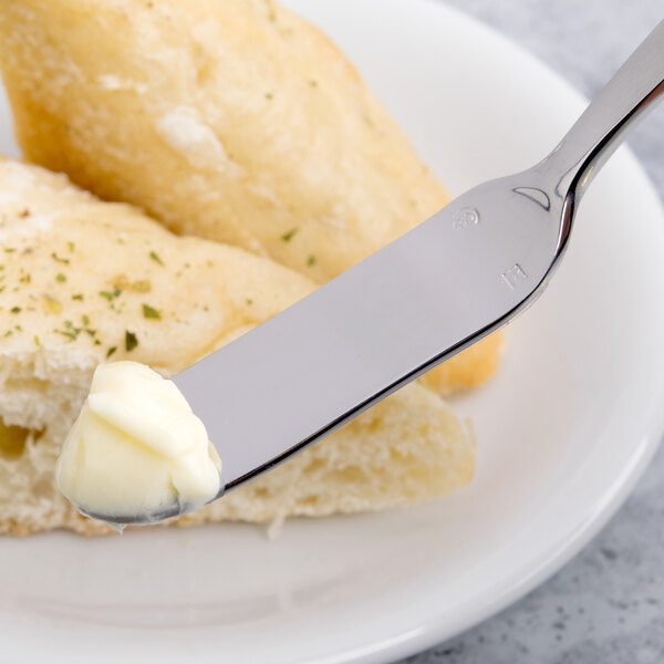 A Chef & Sommelier stainless steel butter knife with butter on it.
