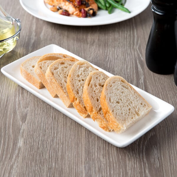 A rectangular white porcelain coupe platter with sliced bread on it.