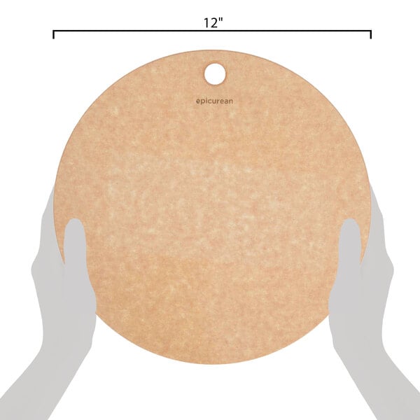 A hand holding a round Epicurean natural wood fiber pizza board.