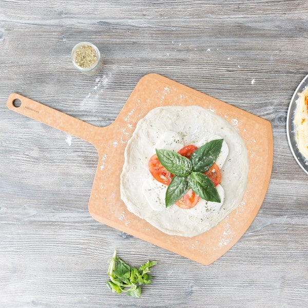 A pizza with tomatoes and basil on a wood pizza peel.