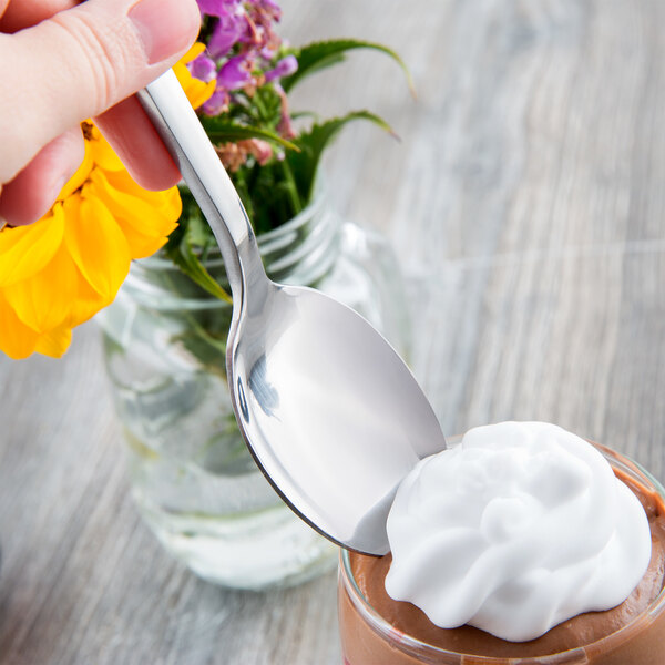 A hand holding a Libbey stainless steel dessert spoon over a chocolate dessert.