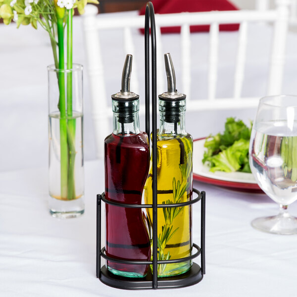 A Tablecraft black olive oil cruet rack holding oil and vinegar bottles on a table.