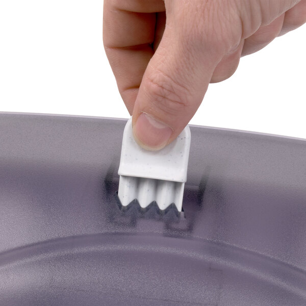 A hand pressing a white object in a San Jamar Oceans towel dispenser.