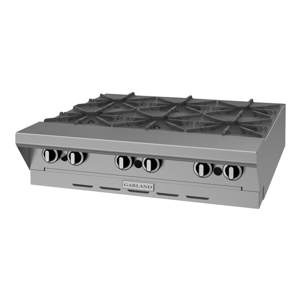 A stainless steel commercial 6-burner gas range top with control knobs on the front.