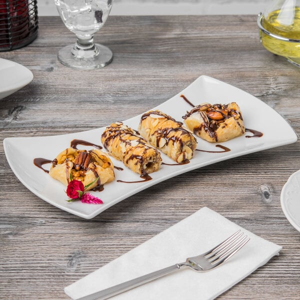 A Schonwald white porcelain bowtie tray with desserts on a table.