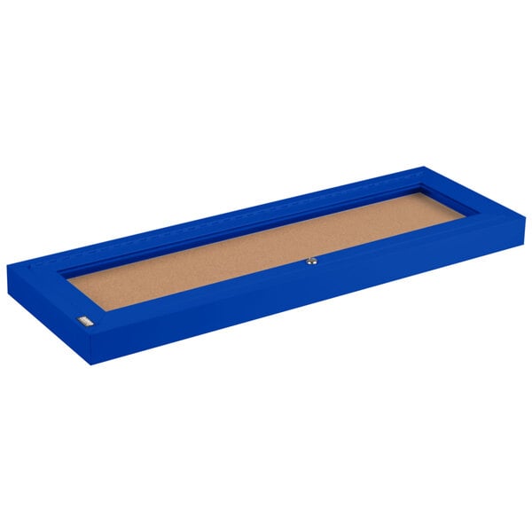 A blue rectangular box with a brown cork board surface.
