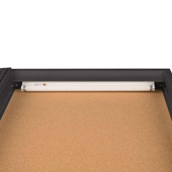 A bronze indoor lighted bulletin board with one door.