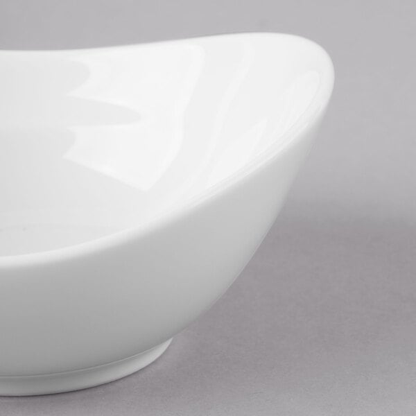 A close-up of a Schonwald white dip dish with a curved edge.