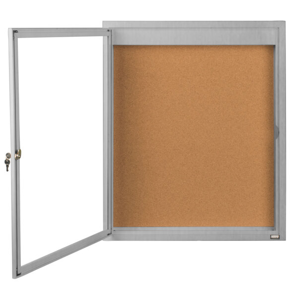 A corkboard with a white door and a silver frame.
