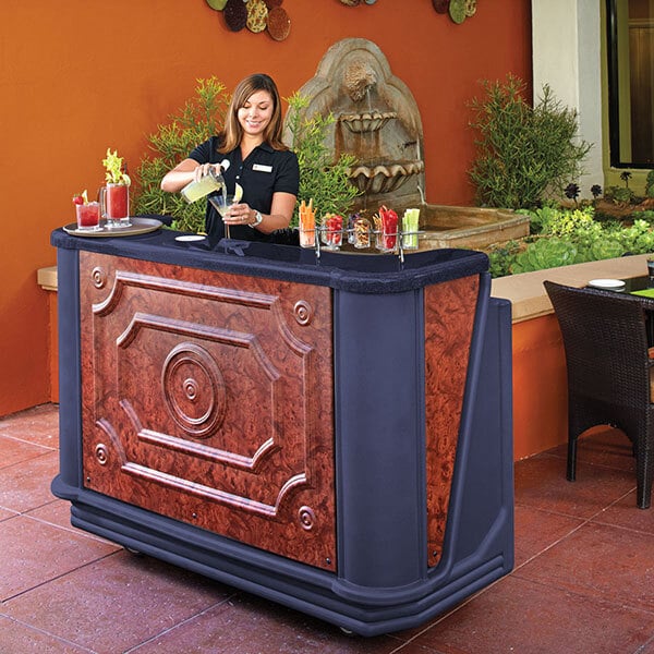 A woman at a Cambro portable bar pouring a drink into a glass.