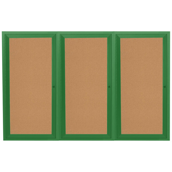 A white indoor bulletin board cabinet with green frames on three doors.