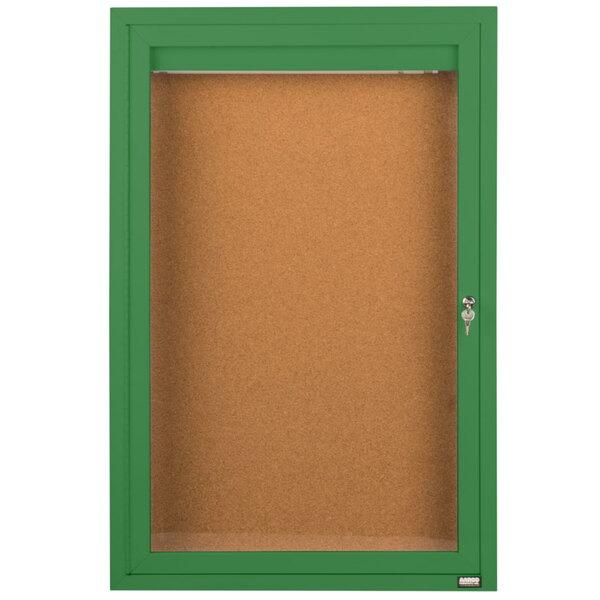 An Aarco green enclosed bulletin board cabinet with a glass door and key lock.