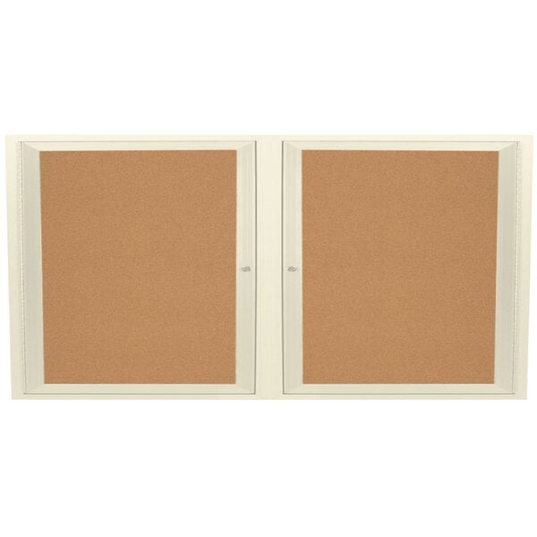 An Aarco ivory enclosed bulletin board cabinet with two doors and cork boards inside.