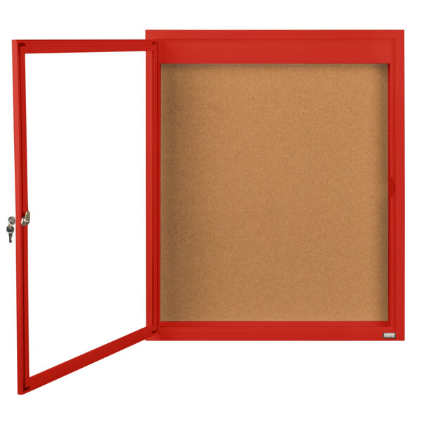 A red framed enclosed bulletin board with a cork interior and a glass door with a lock.
