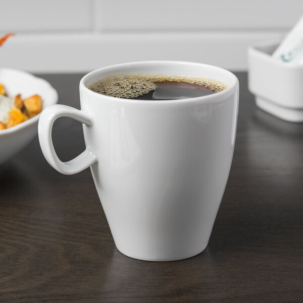 A close up of a white Schonwald Grace porcelain cup with a brown liquid in it.