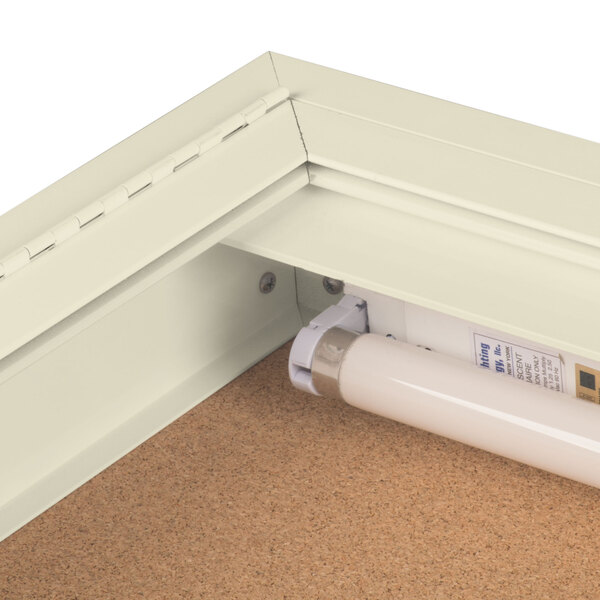 An ivory indoor lighted bulletin board cabinet with a light inside.