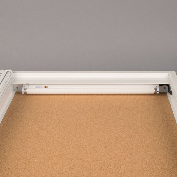 A white Aarco indoor bulletin board cabinet with a light on it.