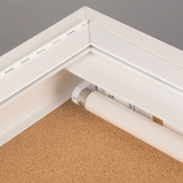 A white Aarco bulletin board cabinet with a light inside.