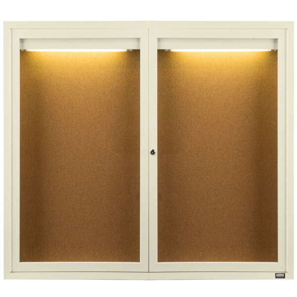 An ivory Aarco cabinet with two doors and a light on it.