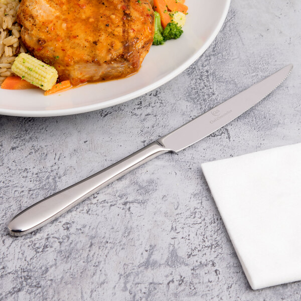 A plate of food with a Chef & Sommelier steak knife on a table.