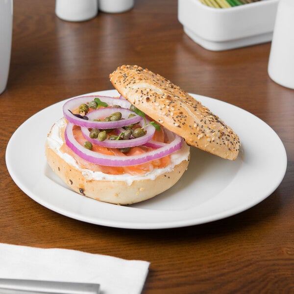 A Schonwald porcelain plate with a bagel sandwich with onions and capers on it.