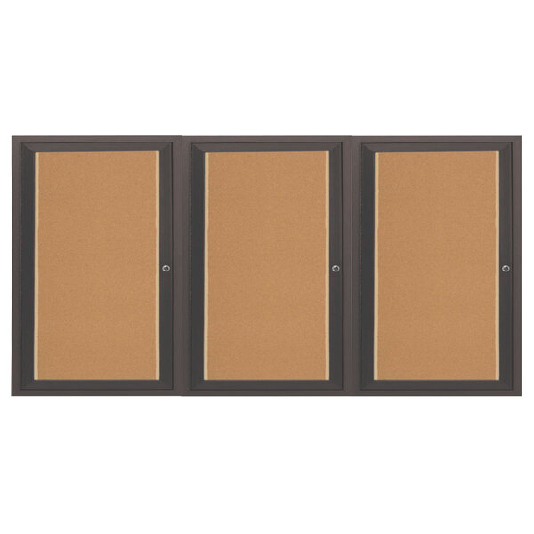 An Aarco bronze indoor bulletin board cabinet with 3 doors and cork boards inside.