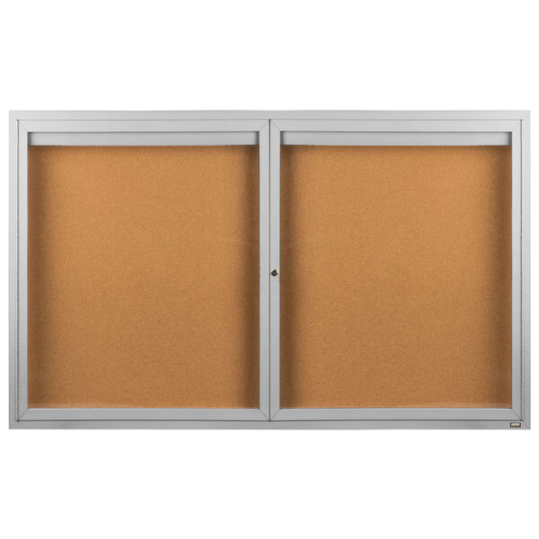 A brown bulletin board with a metal frame behind two glass doors.
