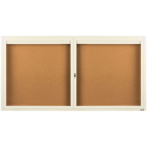 A white framed enclosed bulletin board with two doors and a light inside.