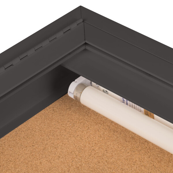 The corner of a bronze Aarco indoor lighted bulletin board cabinet.