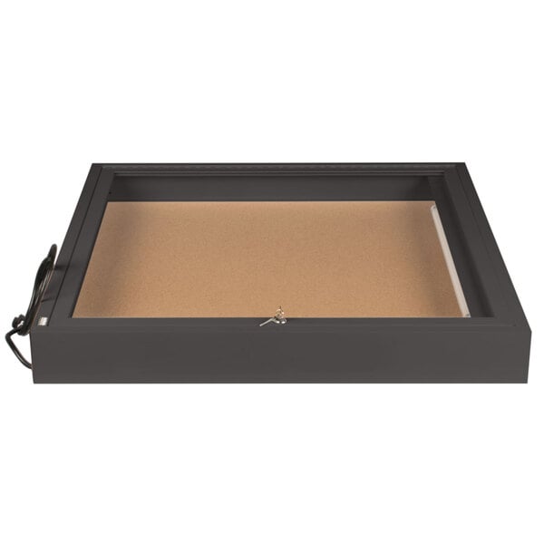 A black rectangular box with a bronze frame and a brown surface with writing inside.