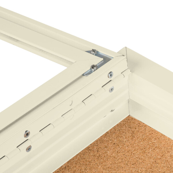 A white metal frame with hinges on a bulletin board cabinet.