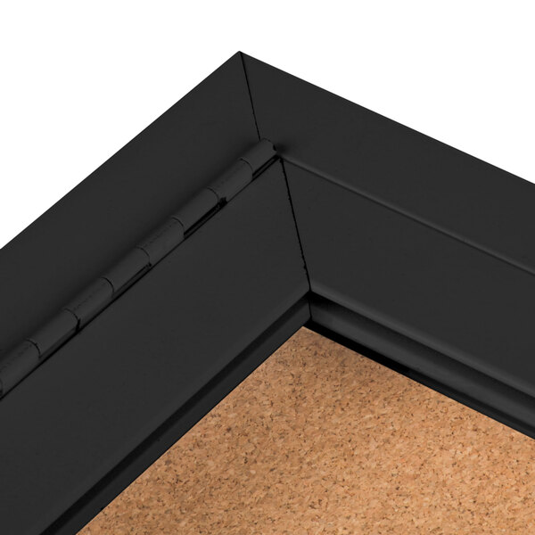 An Aarco black powder coated bulletin board cabinet with a black cork board inside.