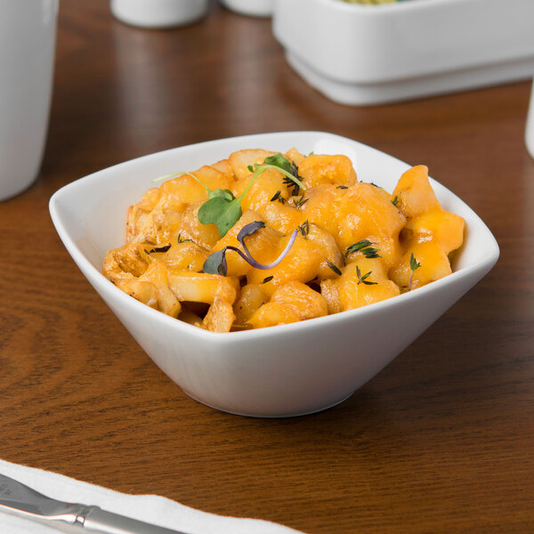 A white Schonwald square porcelain bowl filled with macaroni and cheese on a table.