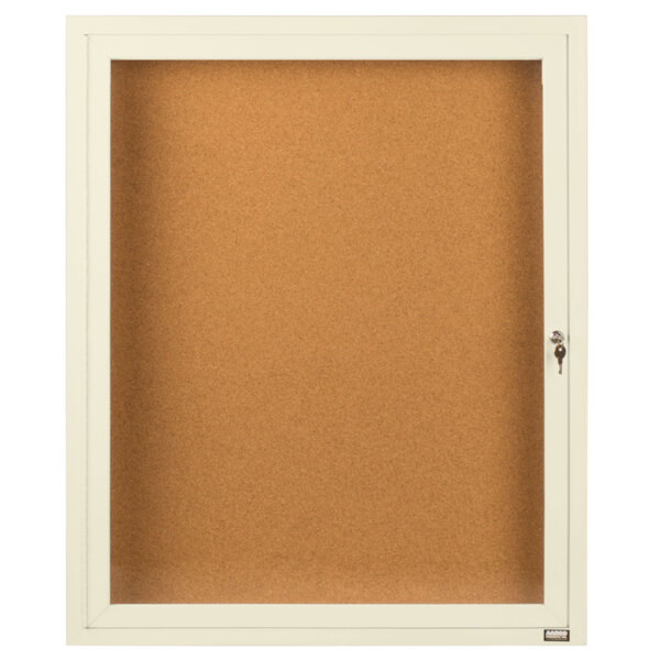 A white framed enclosed bulletin board with a glass door and a key.