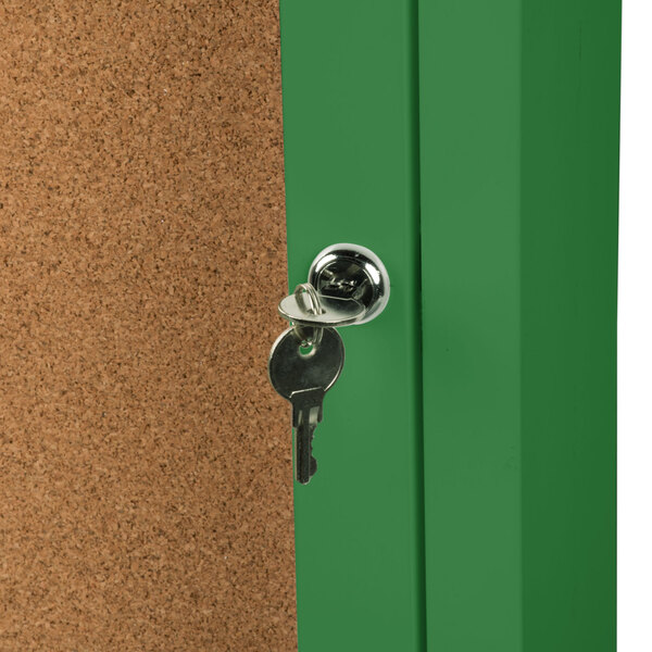 A green Aarco indoor bulletin board cabinet with a key in the lock.