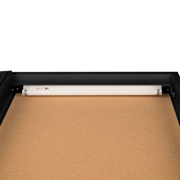 A black Aarco lighted bulletin board cabinet with a white light inside.
