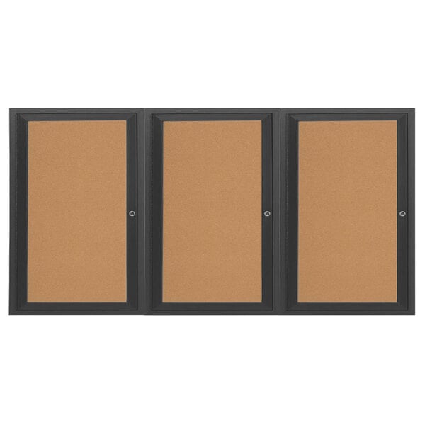A brown bulletin board cabinet with black frames on three doors containing three cork bulletin boards.