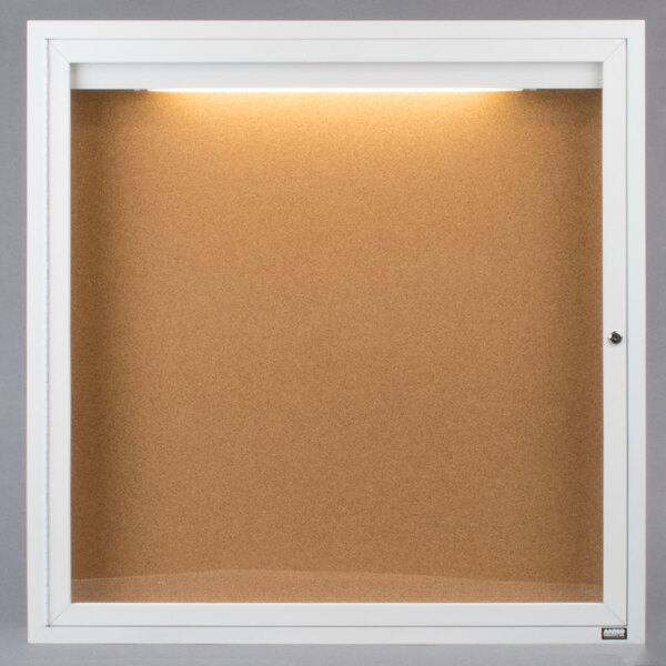 A white frame with a light on it enclosing a bulletin board.
