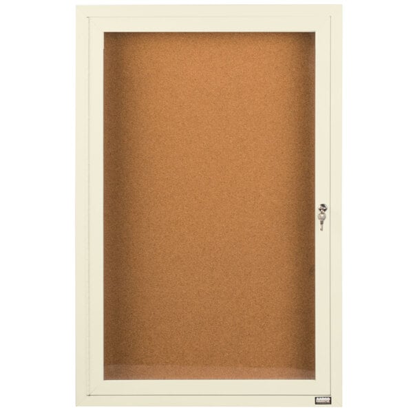 An ivory powder coated enclosed bulletin board cabinet with a door.